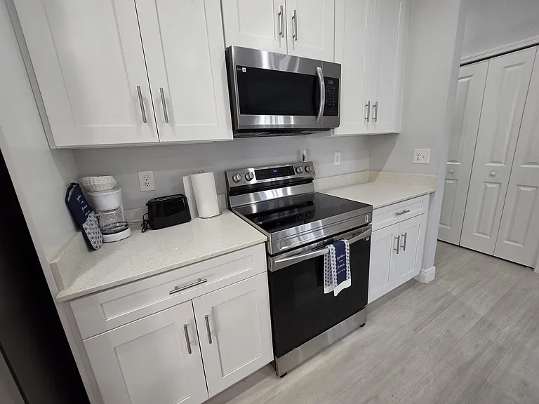Well-equipped kitchen with white shaker cabinetry, ample counter space, and stainless steel range and over-the-range microwav