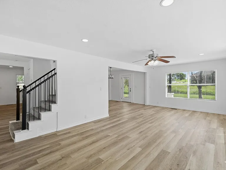Unfurnished living room with healthy amount of natural light, ceiling fan, light wood-style floors, stairs, and recessed lighting