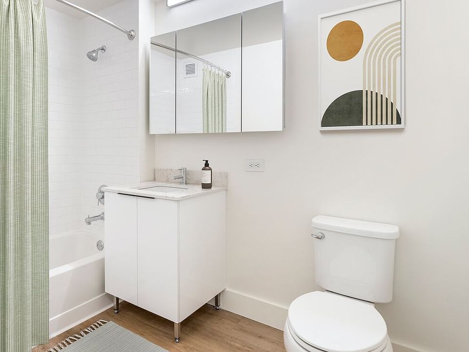 Renovated Package I bath with white marbled quartz countertops, white cabinetry, and hard surface flooring