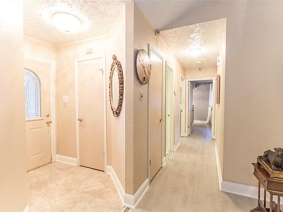 View of the foyer with beautiful ceramic tile and the hallway. Great lighting and neutral wall paint throughout the home.