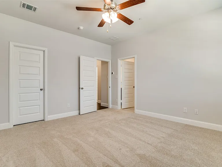 Carpeted room featuring light gray walls, white trim, and a ceiling fan with wood-finish blades