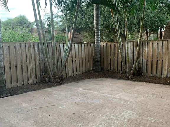 Private tropical fenced in courtyard with shed.
