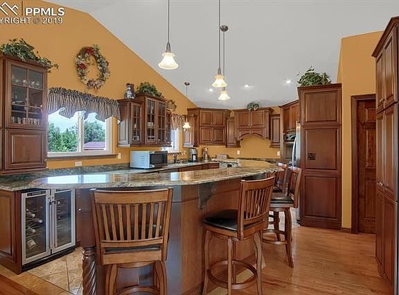 Chef's kitchen with counter bar, built-in wine fridge, marble countertops, soft-close cabinets and pendant lighting