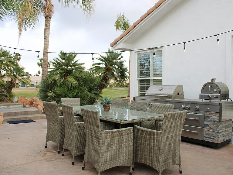 Outdoor kitchen with gas grill and pizza oven. Dining seating for 8. View of the hot tub and golf course.