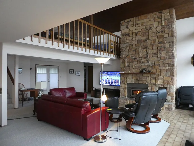 Living area leather furniture and office area in corner by stairs. Wood burning fireplace with heat efficient inset that vents through the house. You can see the view from all points in this room.