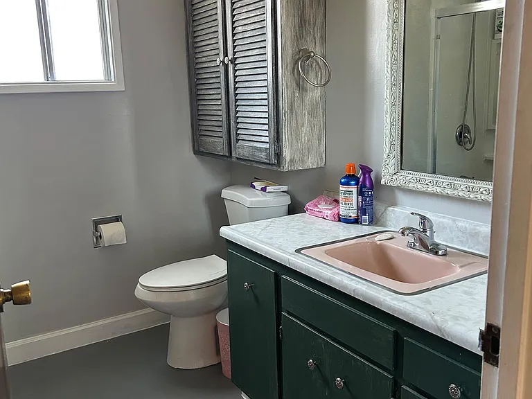 Full bathroom with a single-sink vanity, wall mirror, and window for natural light, plus a shower/tub and extra cabinet stora
