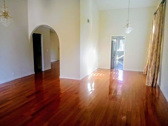 Entry View. Formal Dining Room with Vaulted Ceilings and Chandeliers. Kitchen straight ahead. Family room with Fireplace and Wet Bar at left. Hallway to rest of home at left.