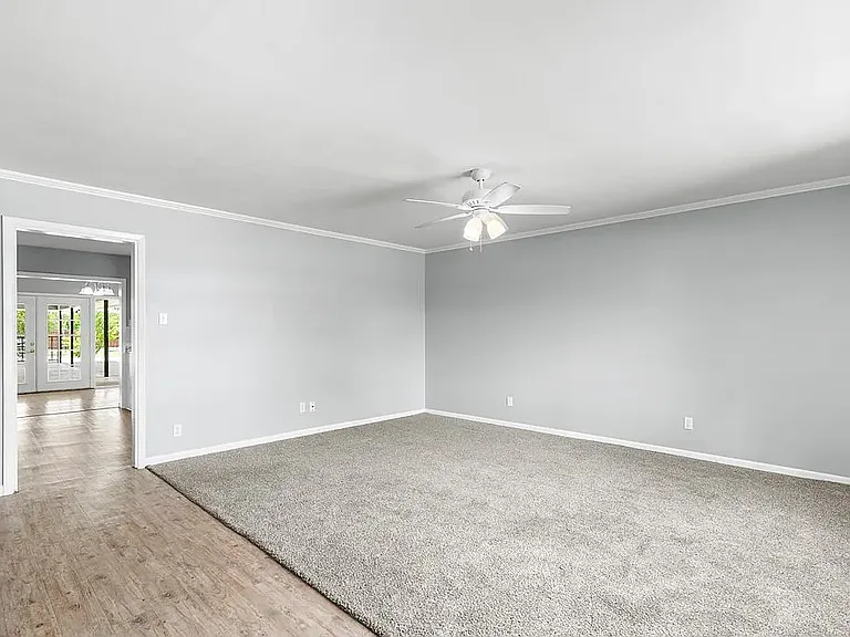 Living Room with new gray carpet, ceiling fan, and fresh gray paint, view into Kitchen, Dining Room, and Back Yard.