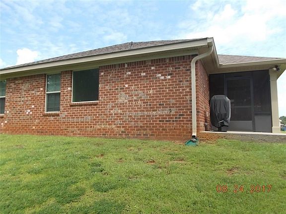 BACK OF THE HOUSE SHOWING SCREENED PORCH AND PATIO