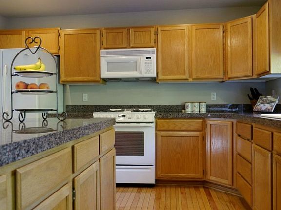 The island kitchen is spacious and features granite countertops and hardwood flooring.