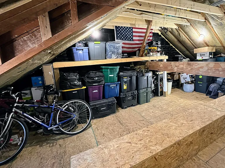 Fully floored, insulated attic with built-in shelves and high ceiling.