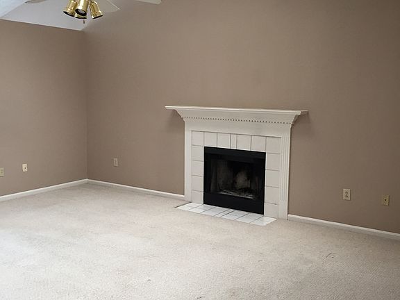 Vaulted ceiling living room with fireplace and ceiling fan.