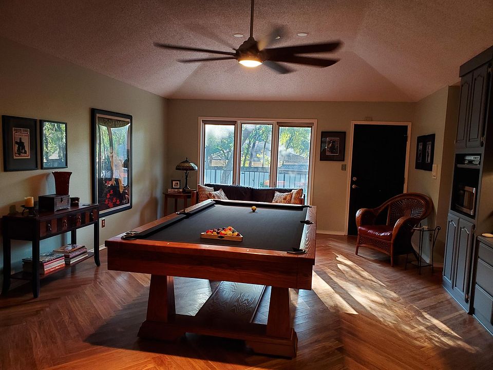 Primary living and dining area. Kitchenette is on the right wall. Entrance is the door to the right of the windows. (Pool table and other furniture have been removed.)