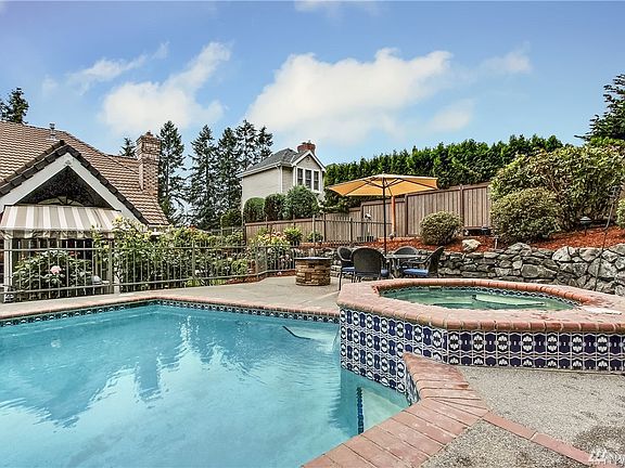 Gorgeous hardscapes of aggregate concrete surfaces edged in brick and Italian tile backsplash.  Fully-fenced pool and hot tub ringed in mature roses.
