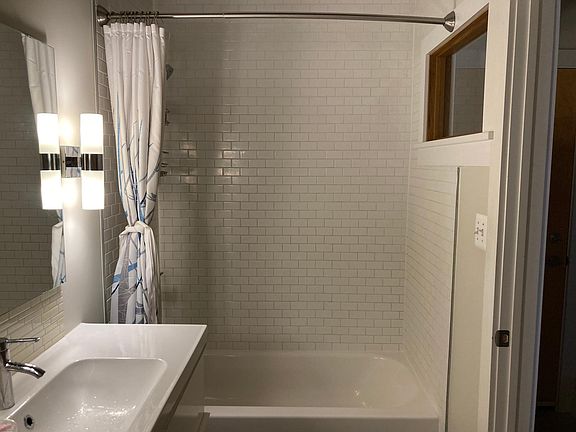 Bathroom with small subway tile, high window to hall for light, bath and shower