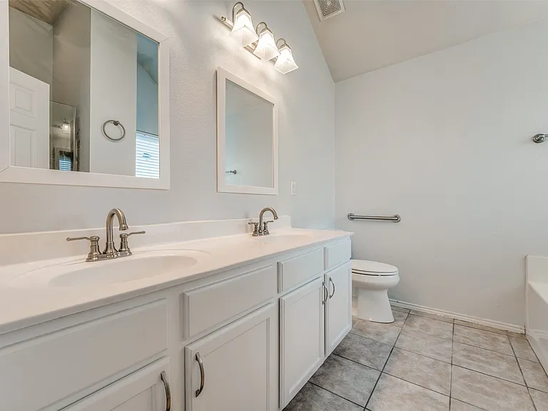 Dual sink vanity with white cabinetry, brushed nickel fixtures, and individual framed mirrors
