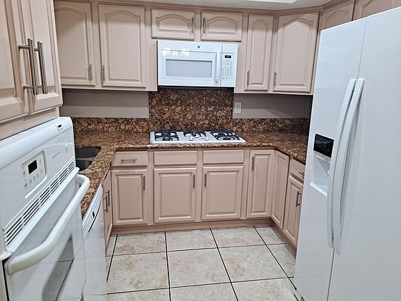 Kitchen view granite counters. Built in stove, five burner stove top, dishwasher, side by side refrigerator.