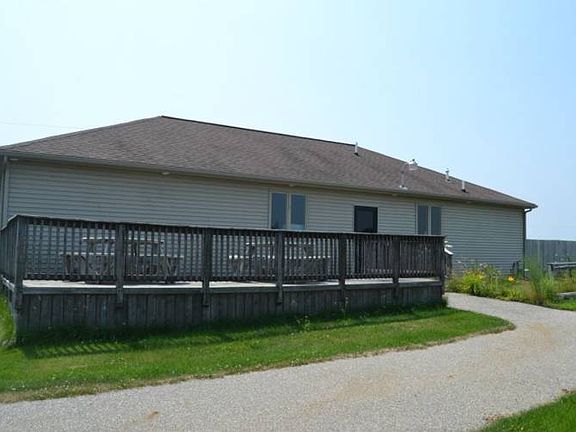 The back of the main building. Large deck is perfect for getting out to enjoy a little lunch in the middle of the day.  The main building contains a large open area with counter that was the pro shop,  2 large storage areas an office and restrooms.  It would be easy to change the configuration of the inside to fit your needs.