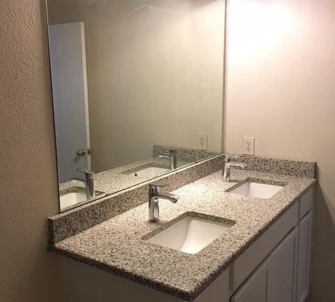 Full bathroom with granite counter top and double sinks