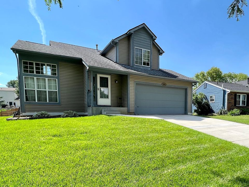 Front yard and newer concrete driveway leading to the attached two car garage.