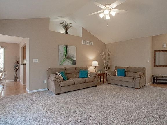 Large living room with vaulted ceilings and lighted plant shelf.