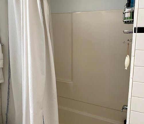 Tub/shower with new shower head and double rod hotel shower curtain rod.