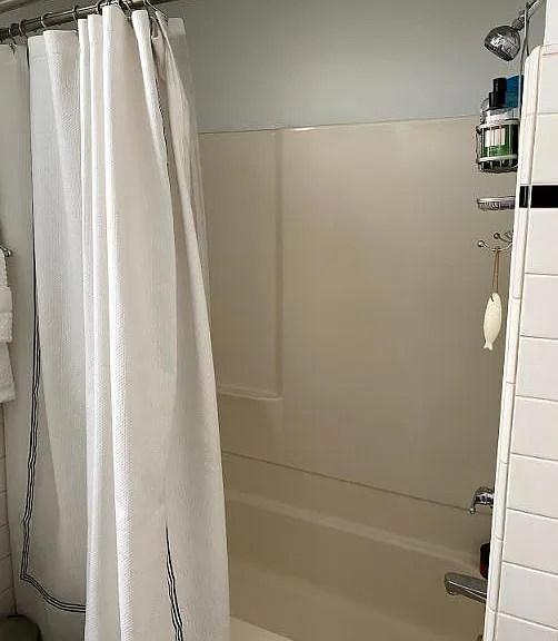 Tub/shower with new shower head and double rod hotel shower curtain rod.
