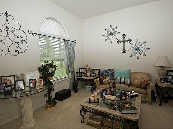 The formal living room features a large arch top window for natural light, carpeting, and the flexib