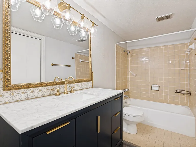 Bathroom featuring a dark vanity with gold hardware, a white countertop, and a built-in sink
