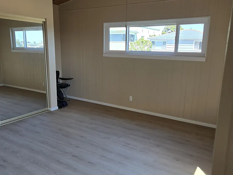 Large bedroom with open beam ceiling and fan.