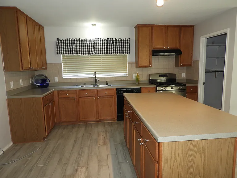 Kitchen with gas stove, island with seating bar with convenient garage entry door.