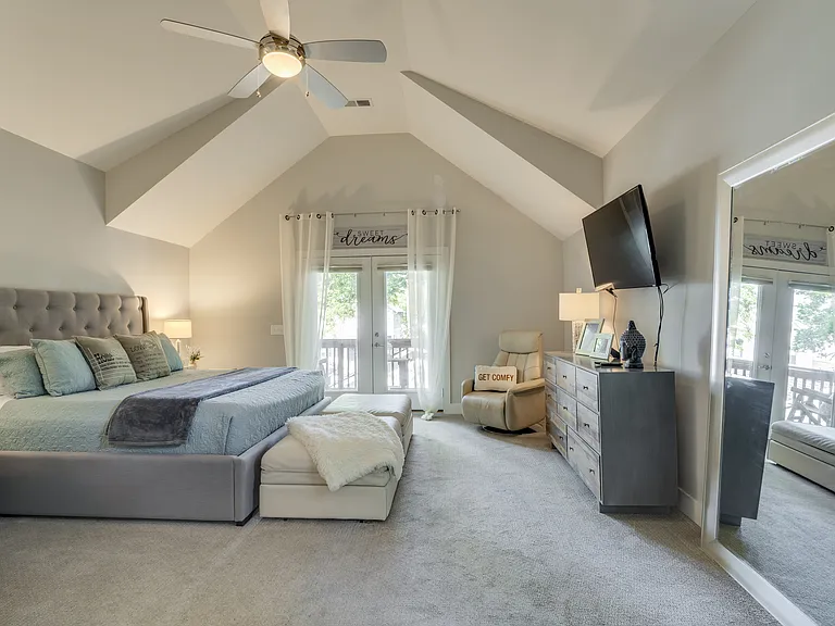 Spacious primary suite with a Roku TV, large dresser, oversized walk-in closet, plush California King bed, two twin ottoman sleepers for flexible, comfortable extended stays.