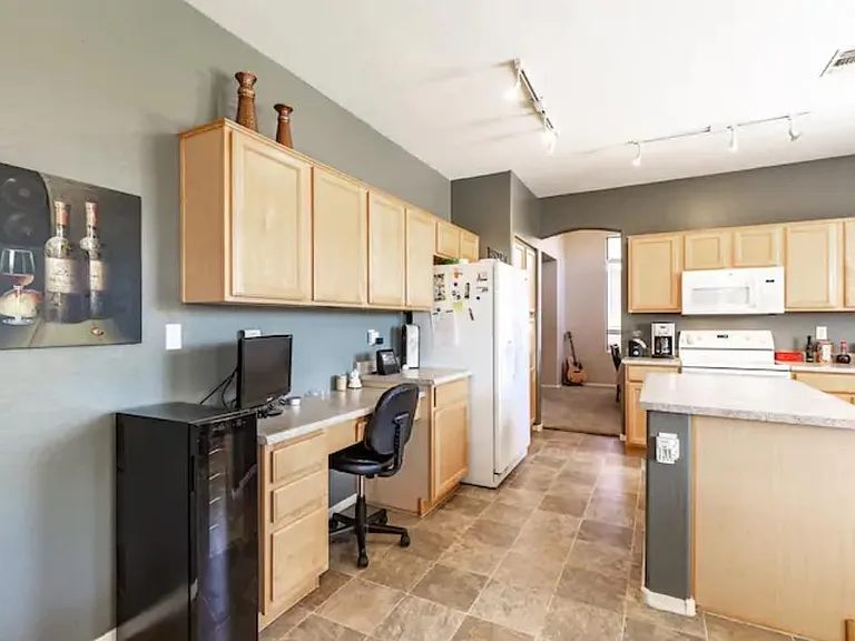 Kitchen features a large center island, desk/chair and dual-zone wine fridge.