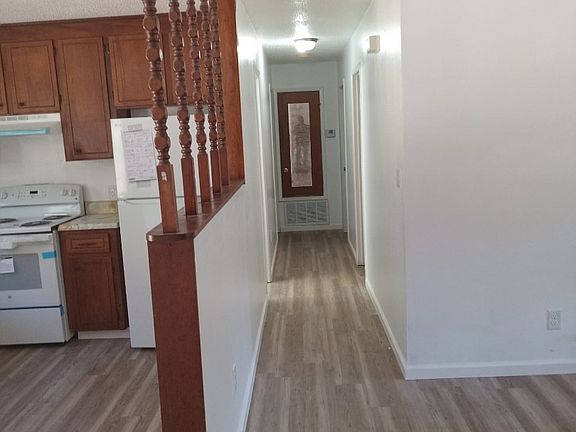 A combination picture of the kitchen, hallway, and living room.