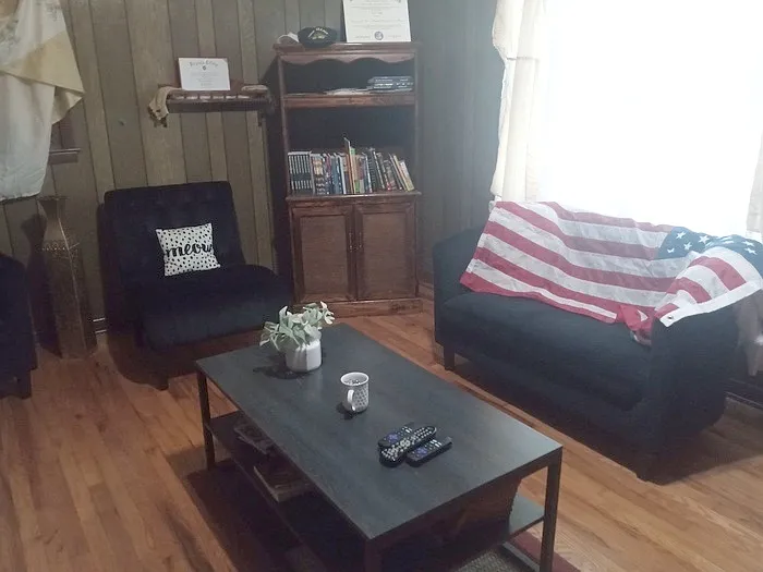 Living room includes: loveseat (slightly larger couch), table, bookshelf, and two chairs, rug, wooden floor.