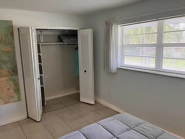 Second bedroom with west-facing windows and a spacious closet with folding doors.