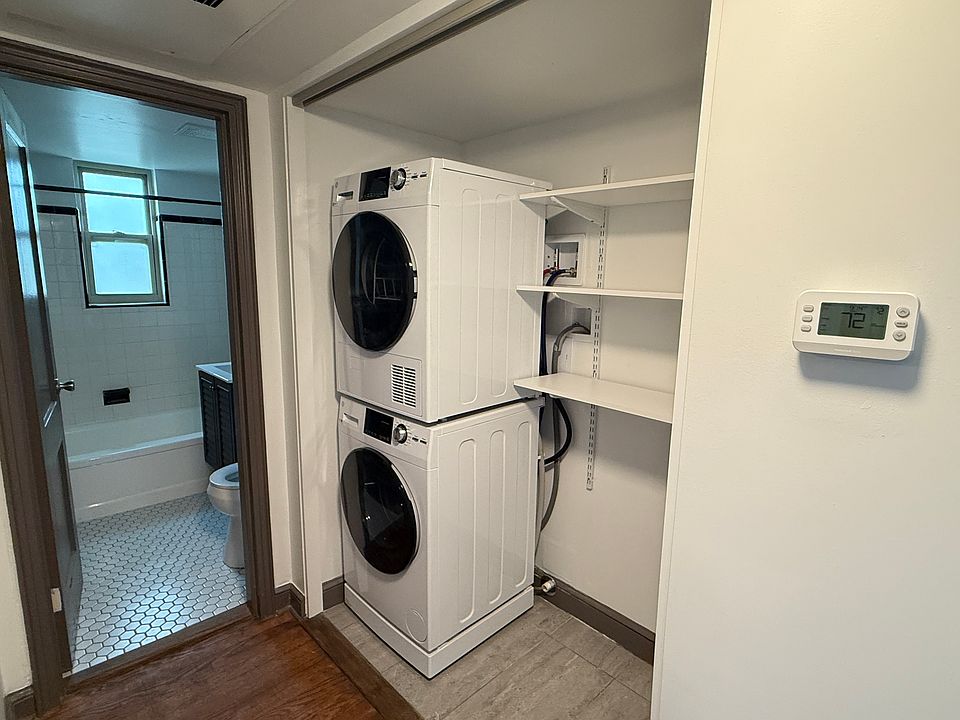 Laundry closet has new GE stacked washer and dryer with storage shelves