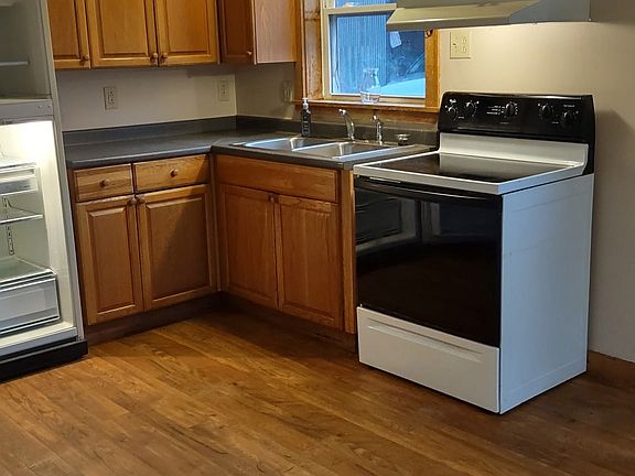 Kitchen with range, refrigerator and window above sink to view out at the forest on the lot
