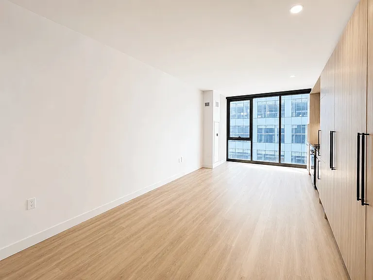 Bright studio living space at Stead 220 in Fulton Market with floor-to-ceiling windows, wide-plank hardwood-style flooring, and abundant natural light.