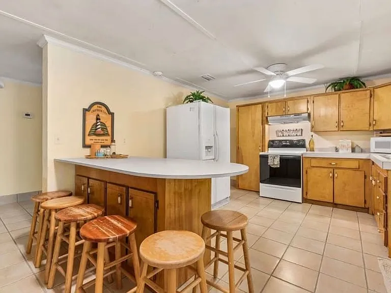 Stove has since been upgraded with a black flat top stove/oven, as well as a stainless steel fridge/freezer.