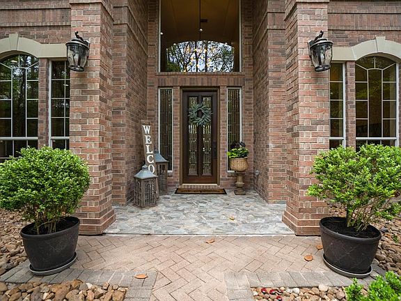 A welcoming front porch framed by brick pillars and a Honduran Mahogany Front Door with leaded glass inserts leads into an elegant foyer. The home has a brick exterior which is low maintenance.