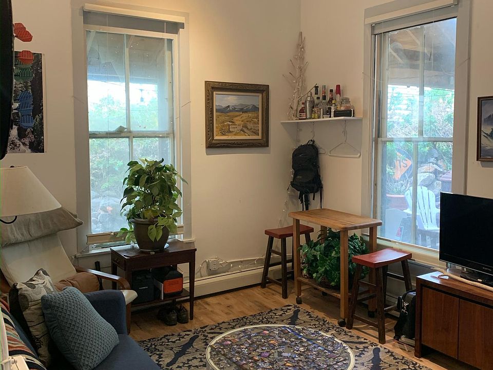 You walk into the living room. Tall ceilings, large windows. Leads out to a patio.