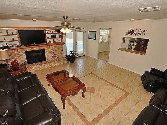 Living area with wood burning fireplace, mantel and shelving. Note the pass thru window to the kitch