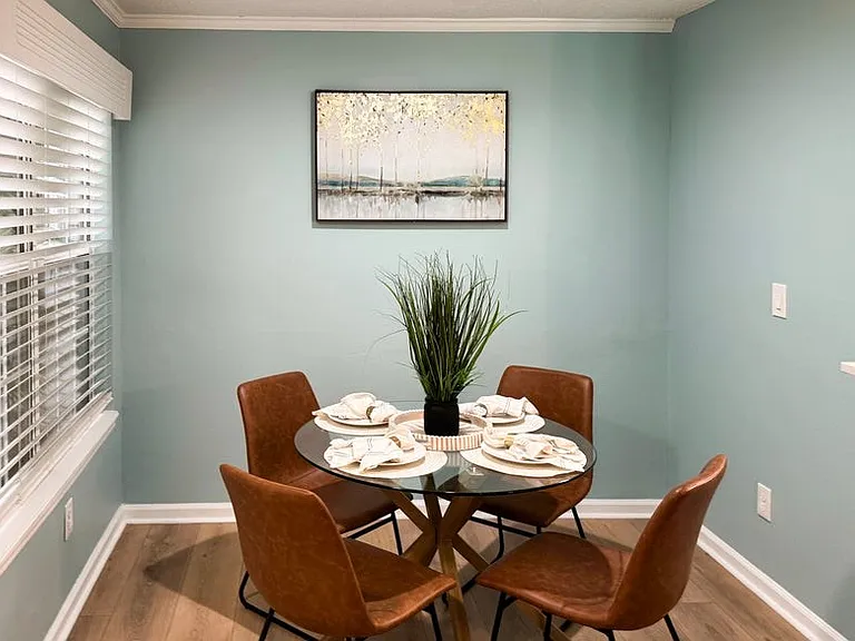 Dining area enjoys filtered sunlight with tropical plant in front of the window.
