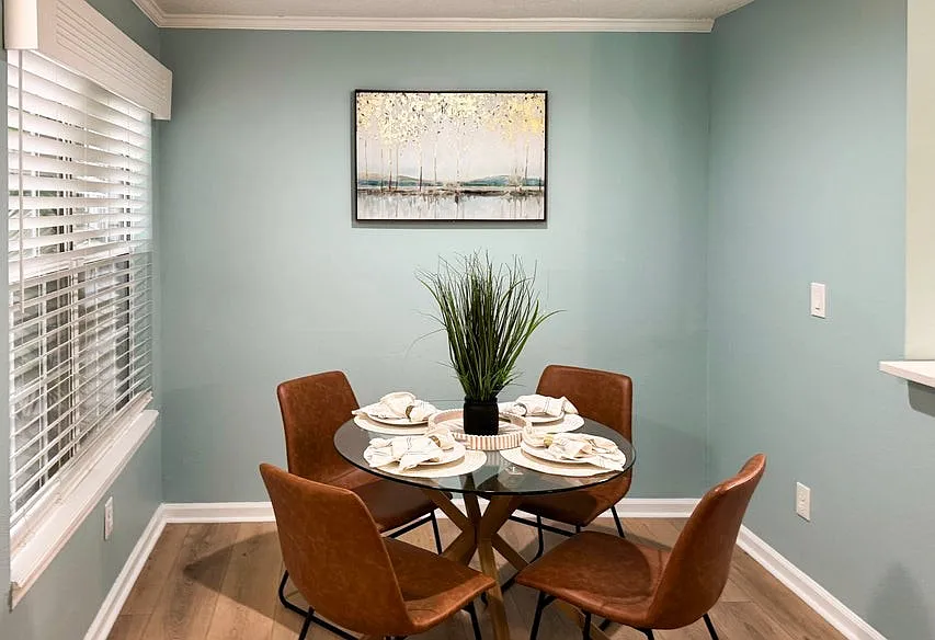 Dining area enjoys filtered sunlight with tropical plant in front of the window.