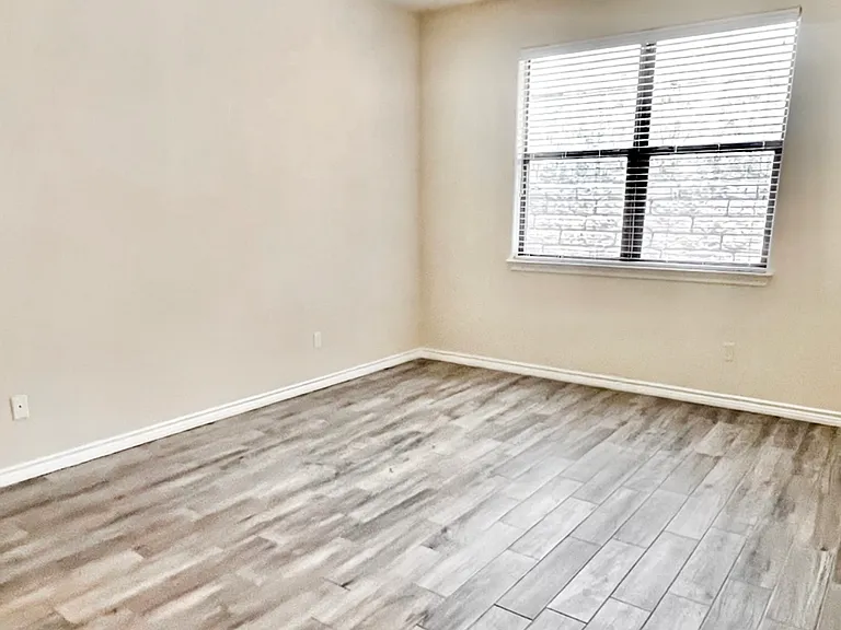 Spacious primary bedroom with a large window offering private backyard view and plenty of natural light