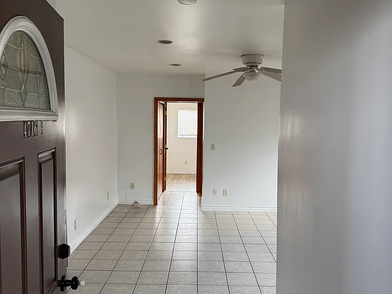 Front door entrance, showing the living room with ceiling fan, the hallway all the way to the bedroom.