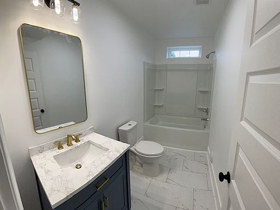 Renovated bathroom with tile floor, new vanity and modern lighting fixtures.