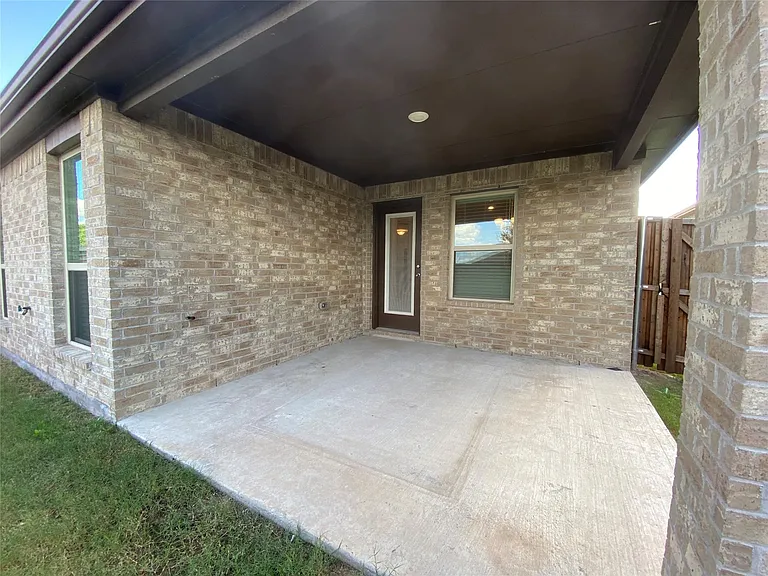 This spacious outdoor living area features a beautifully finished covered concrete patio, perfect for relaxing or entertaining guests. The space is elegantly illuminated by modern recessed lighting integrated into the ceiling, creating a warm and inviting