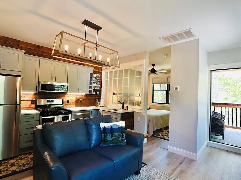 Full kitchen with table behind the couch, king bedroom and entry to the Screen Porch.